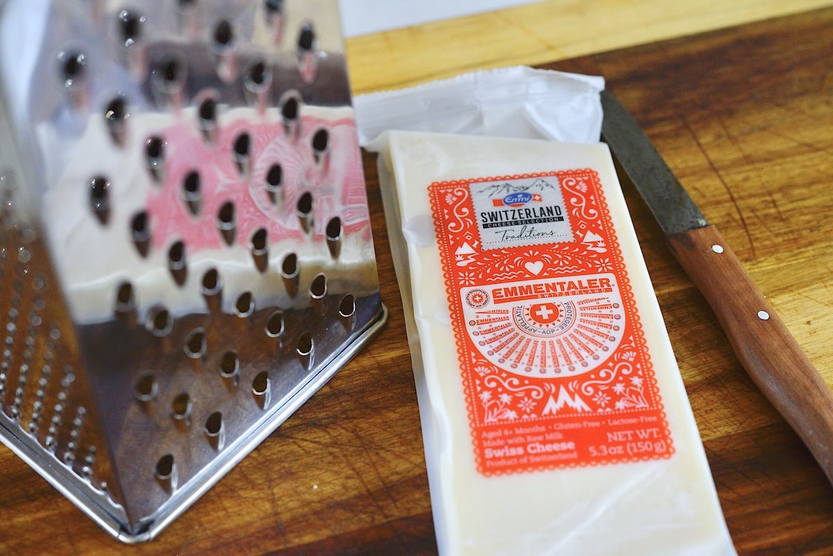 A large block of white cheese next to a box grater.