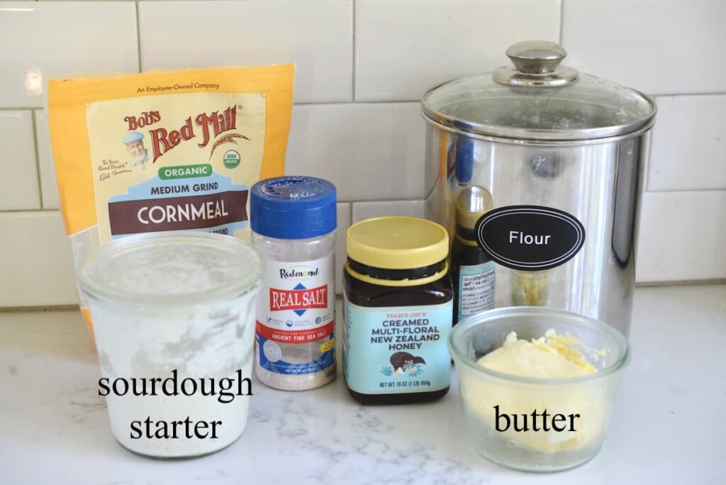 cornmeal, salt, honey, flour, sourdough starter, and butter on kitchen counter