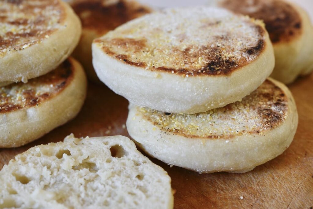 sourdough English muffins stacked on wooden cutting board