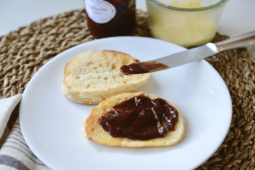 sourdough English muffins cut open on with plate with jam and butter