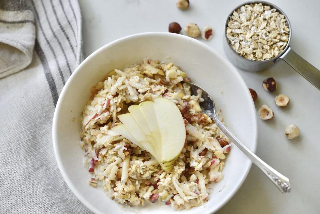 bowl of Bircher muesli with hazelnuts and oats on kitchen counter with towel