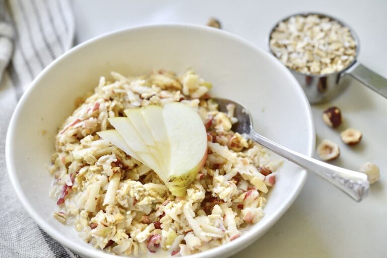 white bowl of Bircher muesli with apple slices and spoon