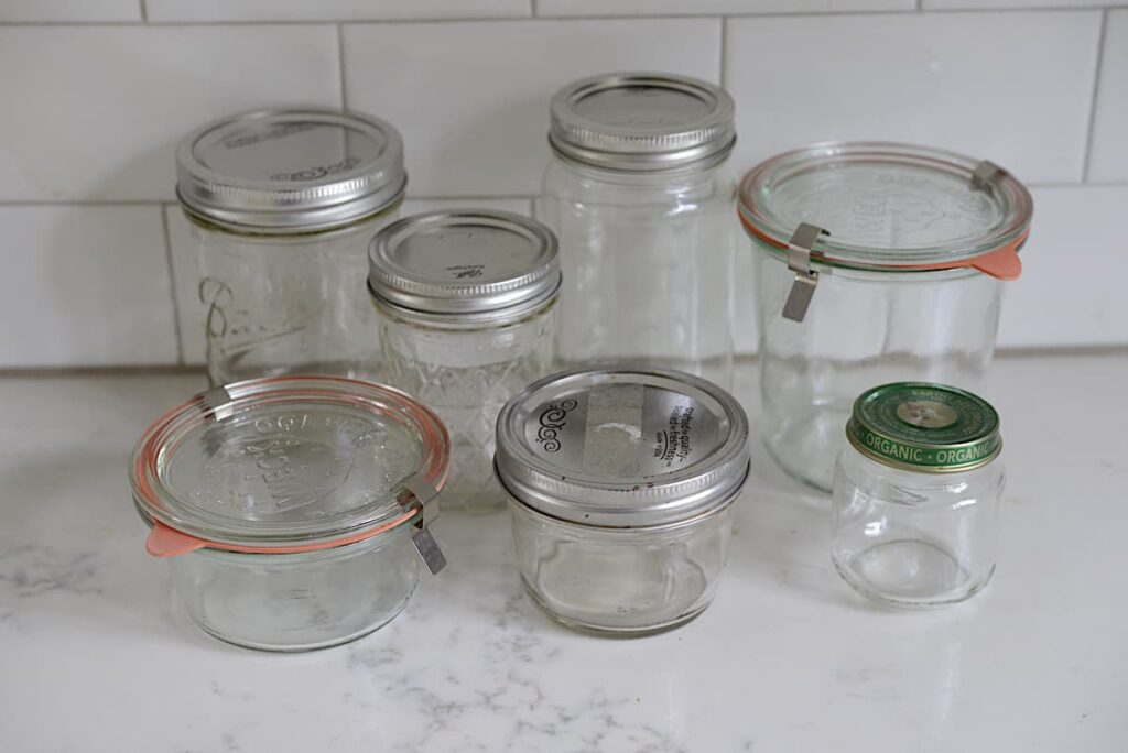 seven different glass jars with lids on kitchen counter