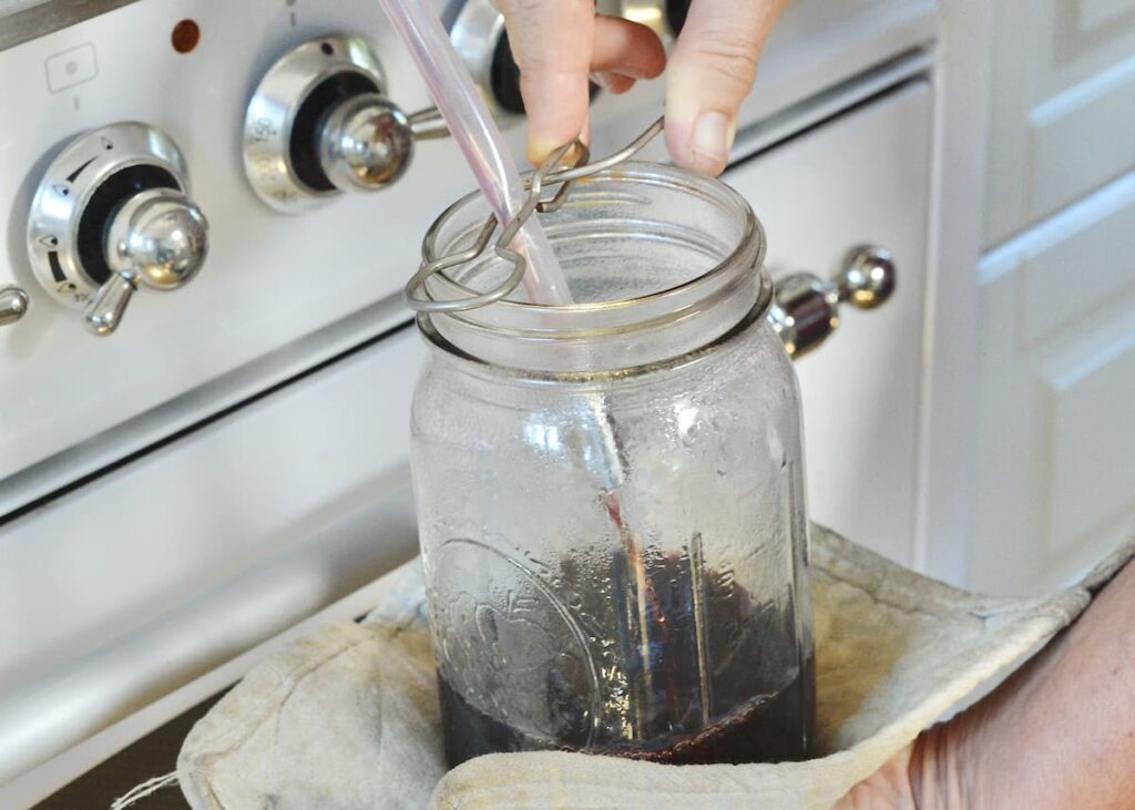 elderberry juice flowing into a mason jar in front of stove