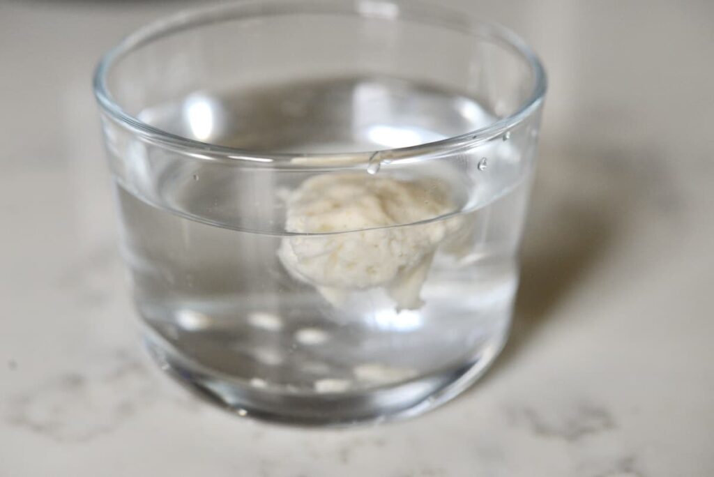 drop of sourdough starter floating in a glass of water