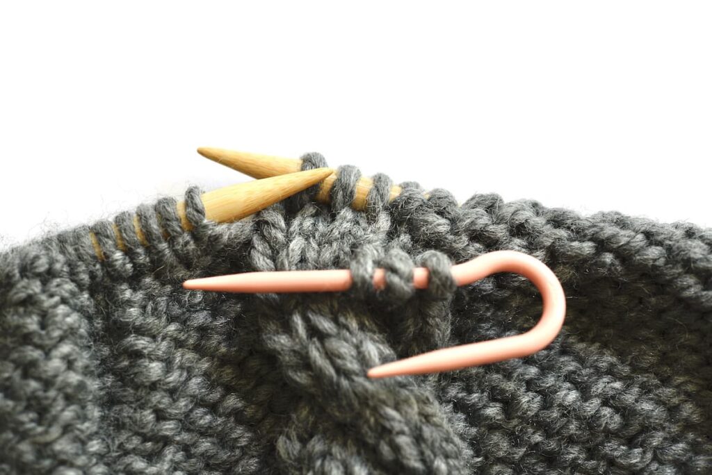 knitted piece with needles and a cable needle to make knit cables