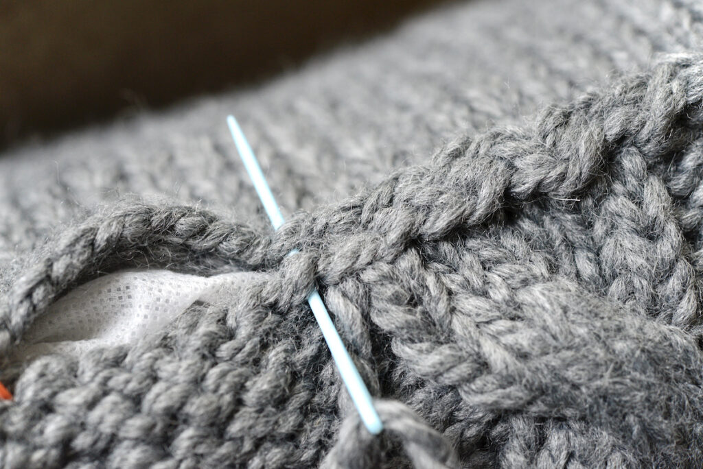 closing the seam of chunky knit pillow with darning needle