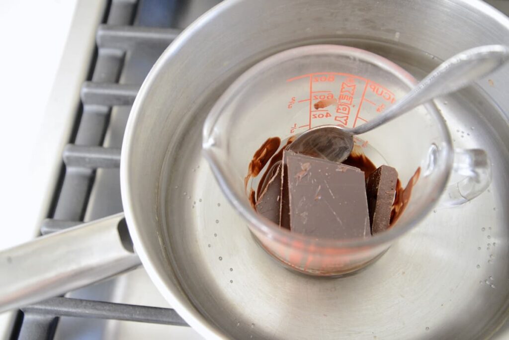 melting chocolate in glass measuring cup in water bath