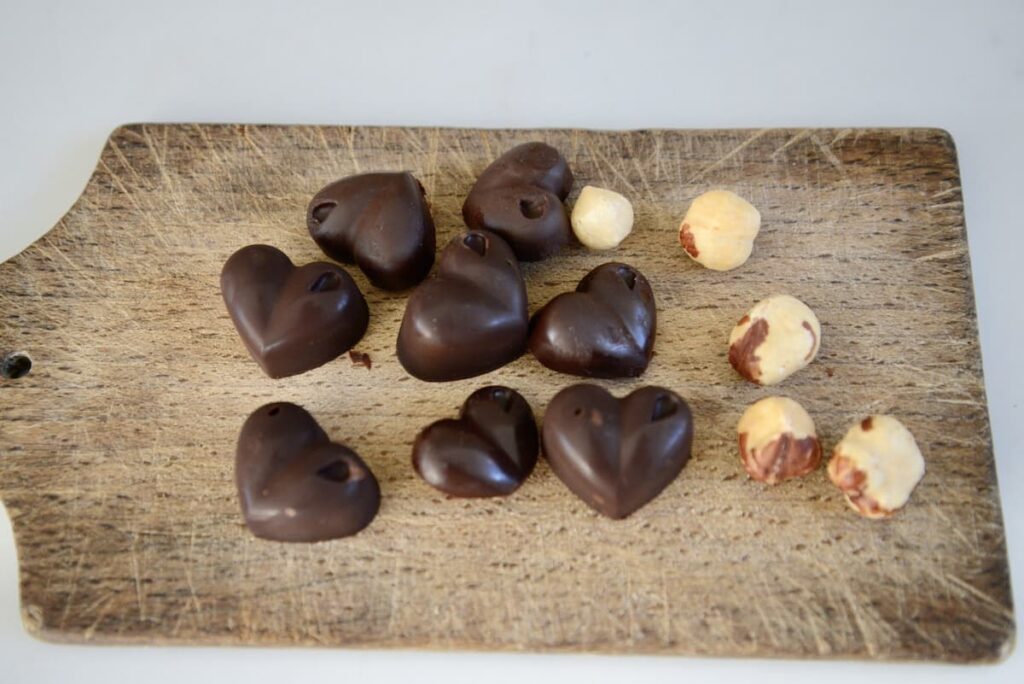 chocolate hearts and hazelnuts on wooden cutting board