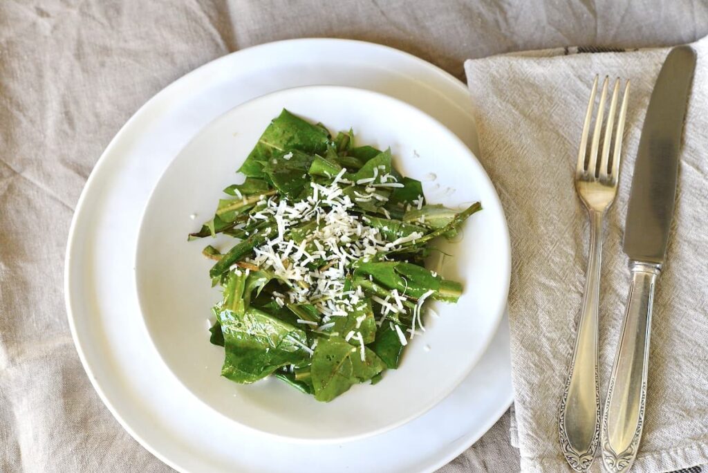 dandelion salad with grated parmesan on white plate
