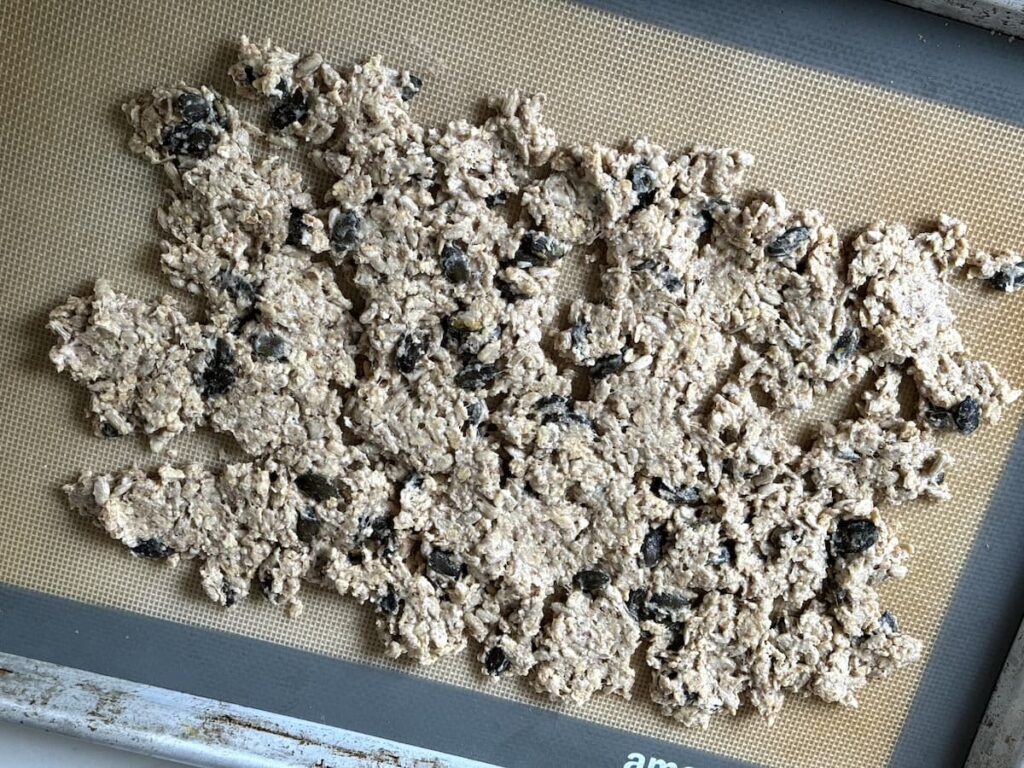 sourdough granola spread out on silicone baking mat