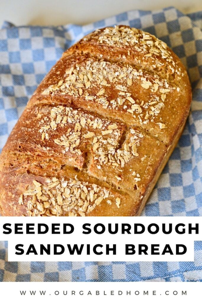 loaf of seeded sourdough sandwich bread on kitchen towel