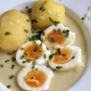 plate with potatoes and eggs in mustard sauce sprinkled with chopped chives
