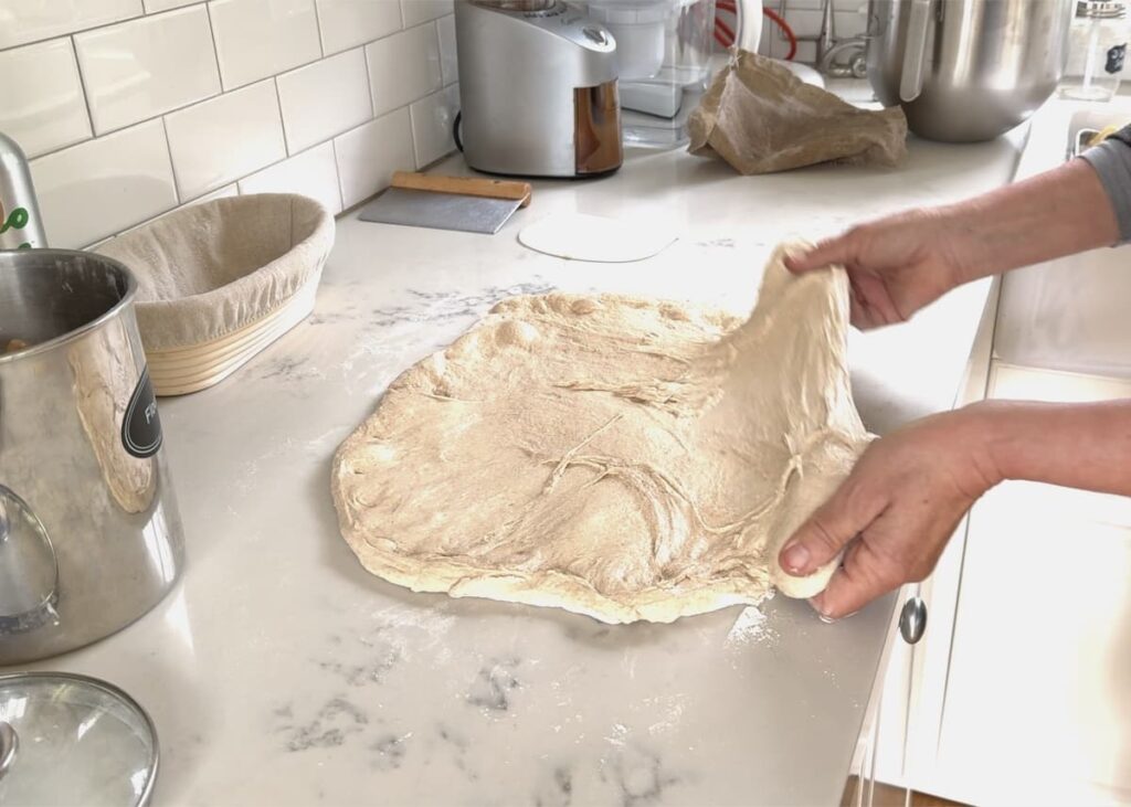woman stretching dough into rectangle on kitchen counter