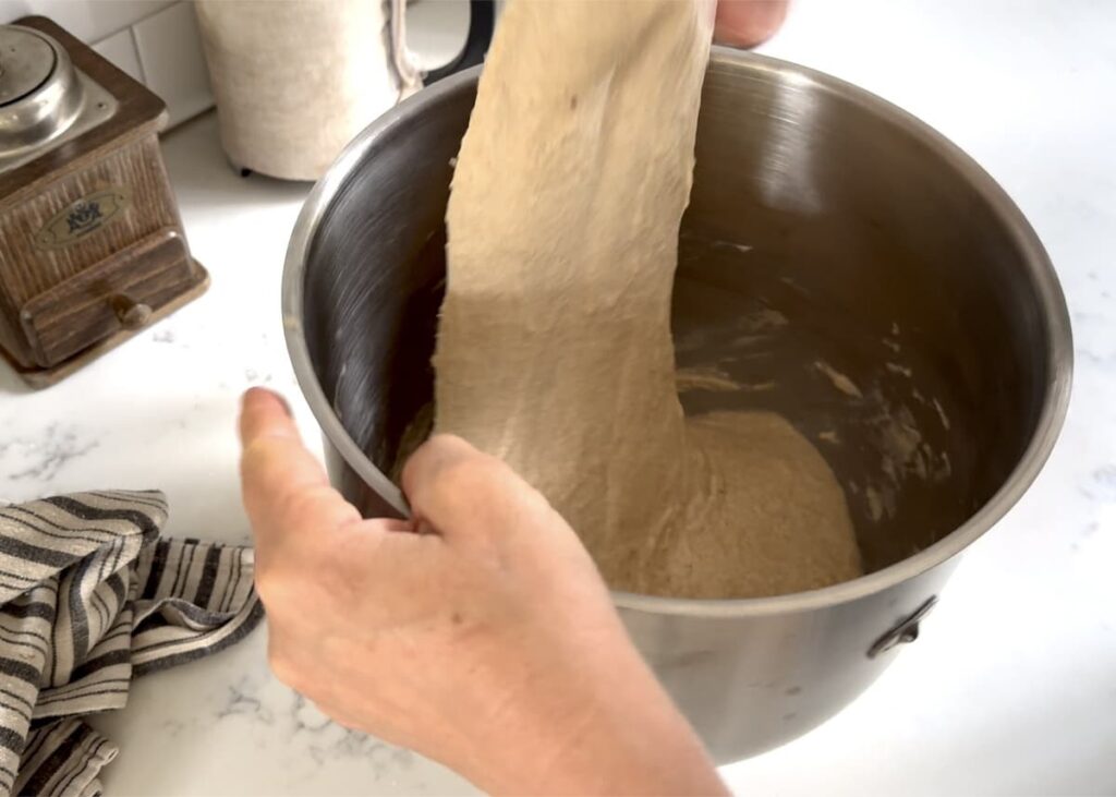 hand stretching dough in a large mixing bowl