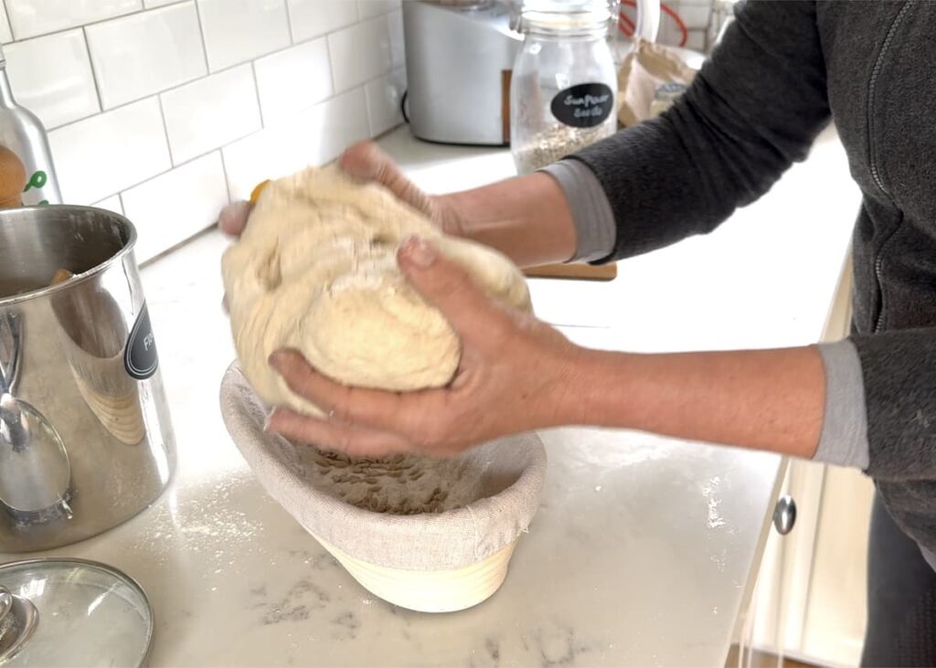 woman transferring dough log into oval proofing basket
