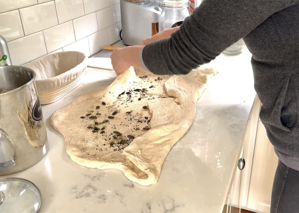 woman folding stretched out dough with seeds