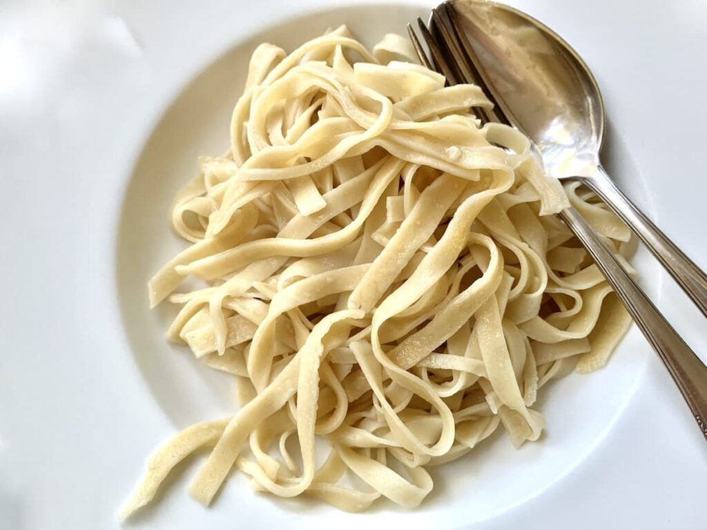 homemade sourdough fettucini on a plate with spoon and fork
