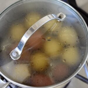 boiling potatoes in pot with glass lid on stove