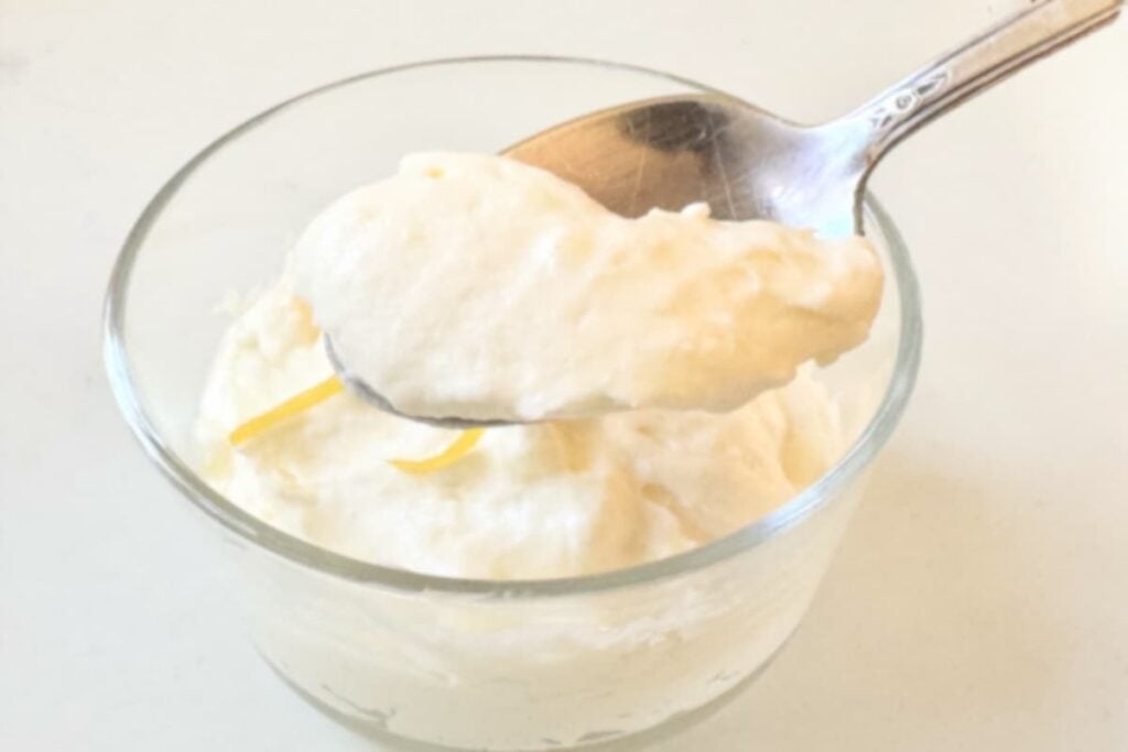 spoon with lemon mousse over a small bowl with more lemon mousse