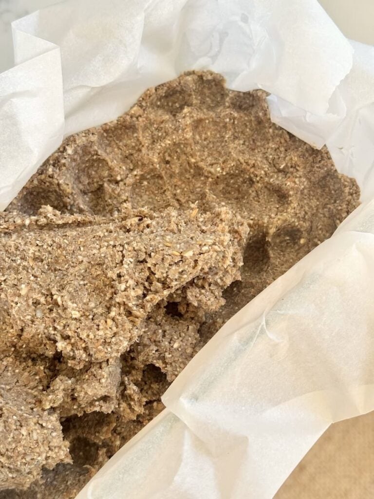 Bread dough being pressed into parchment-lined loaf pan
