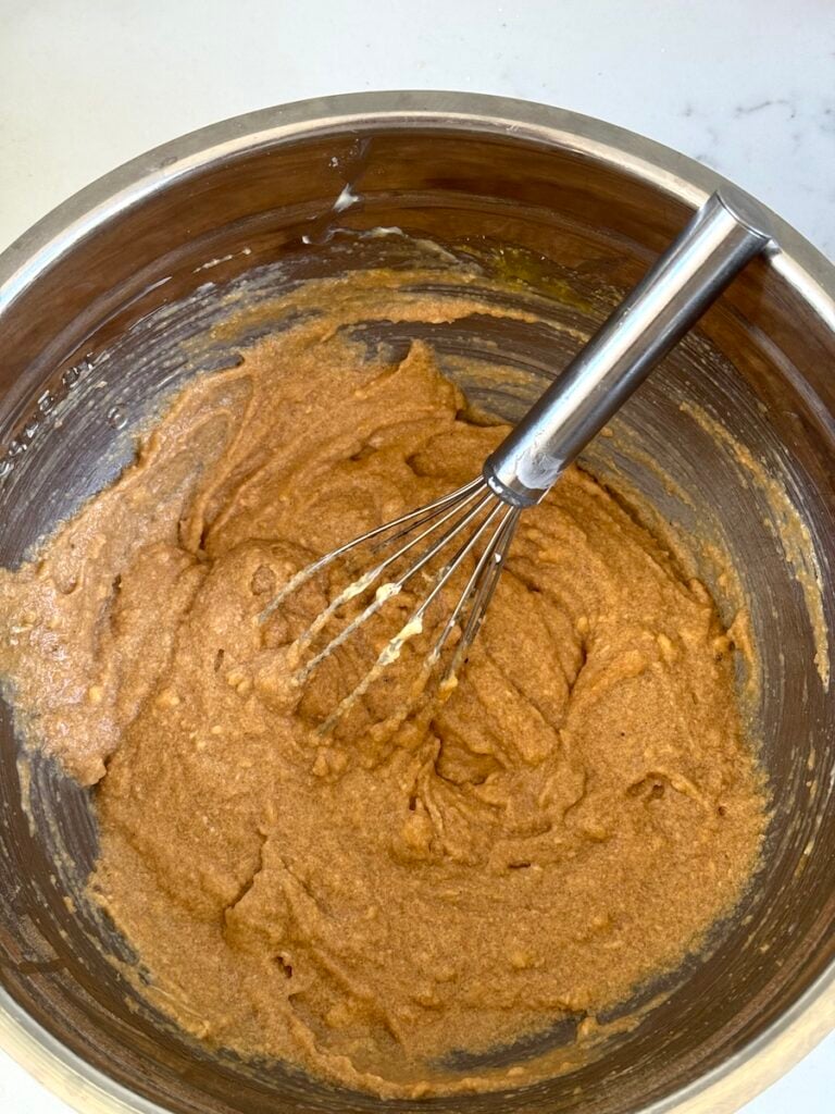 apple cake ingredients mixed up in bowl with wire wisk