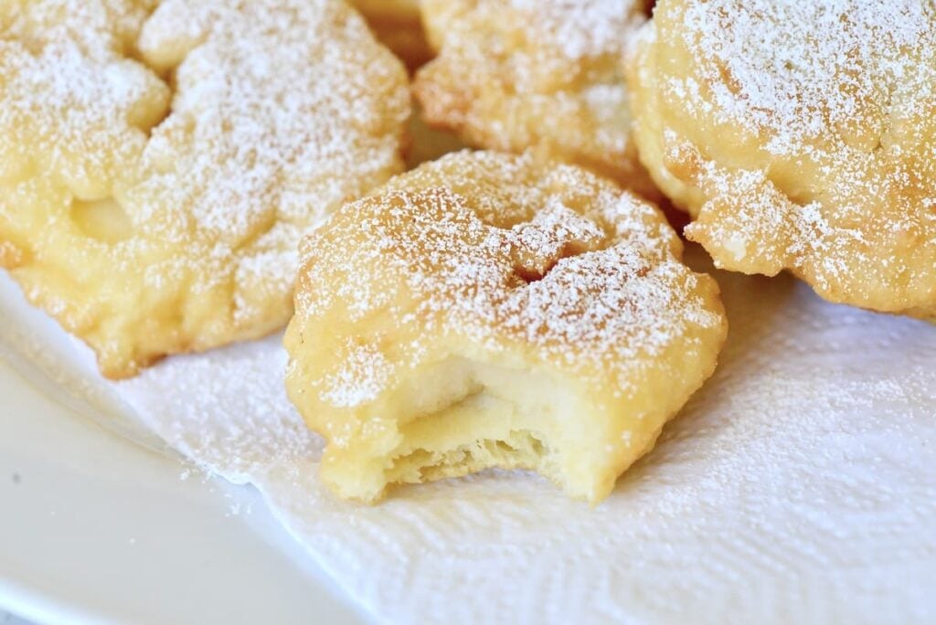 Apfelküchle dusted with powdered sugar with bite taken out of one