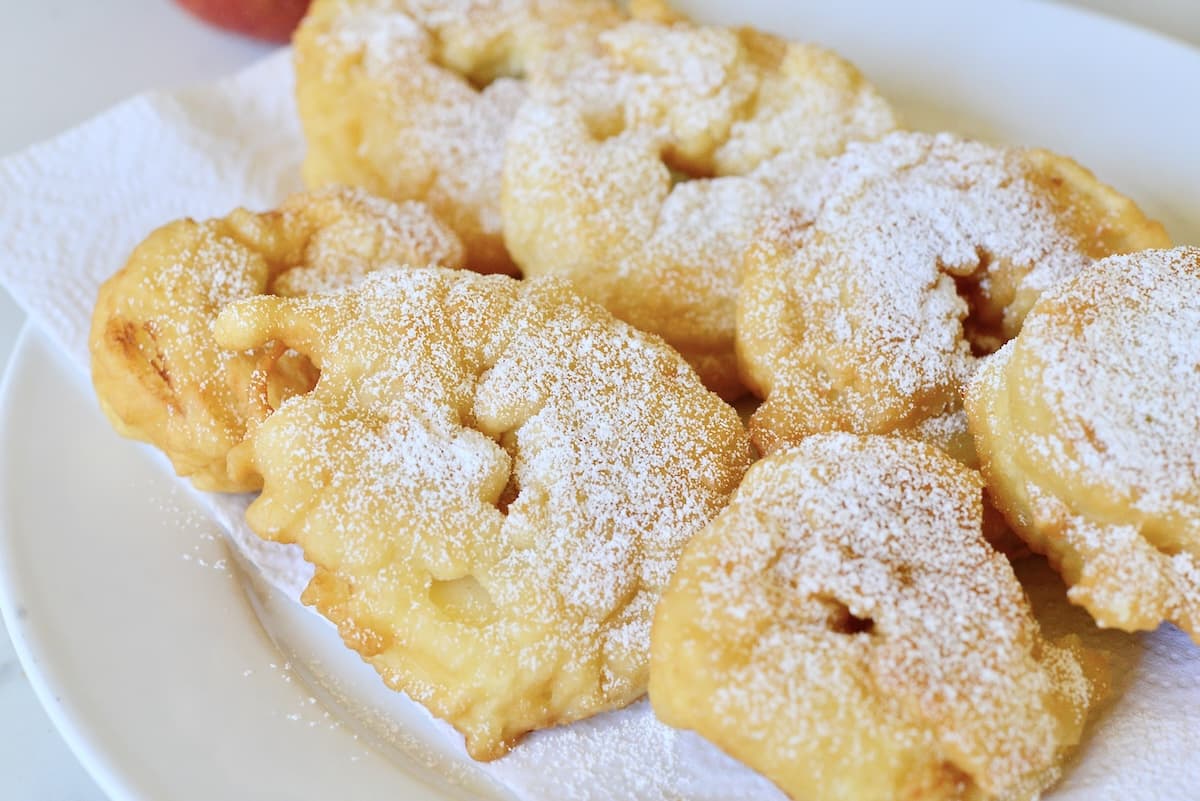 German fried battered apple rings dusted with powdered sugar on plate