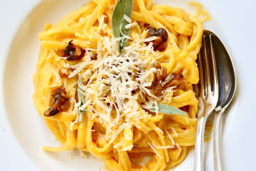 butternut squash pasta with parmesan, chopped walnuts, and sage on plate