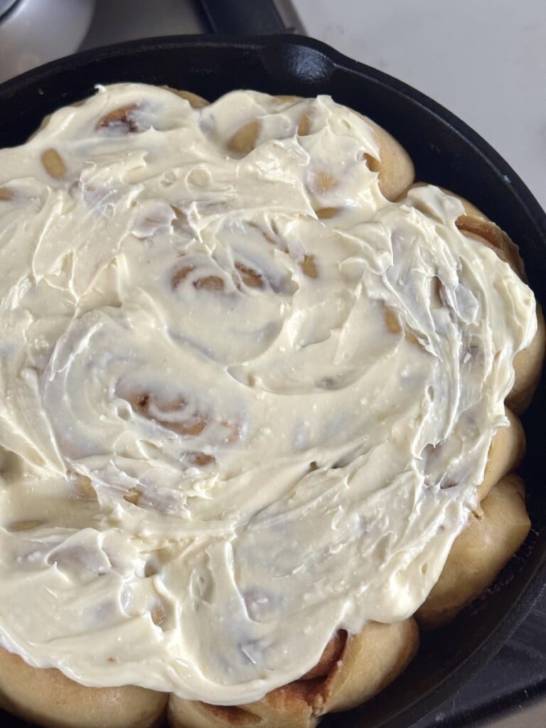 cinnamon rolls with cream cheese glaze in cast iron skillet
