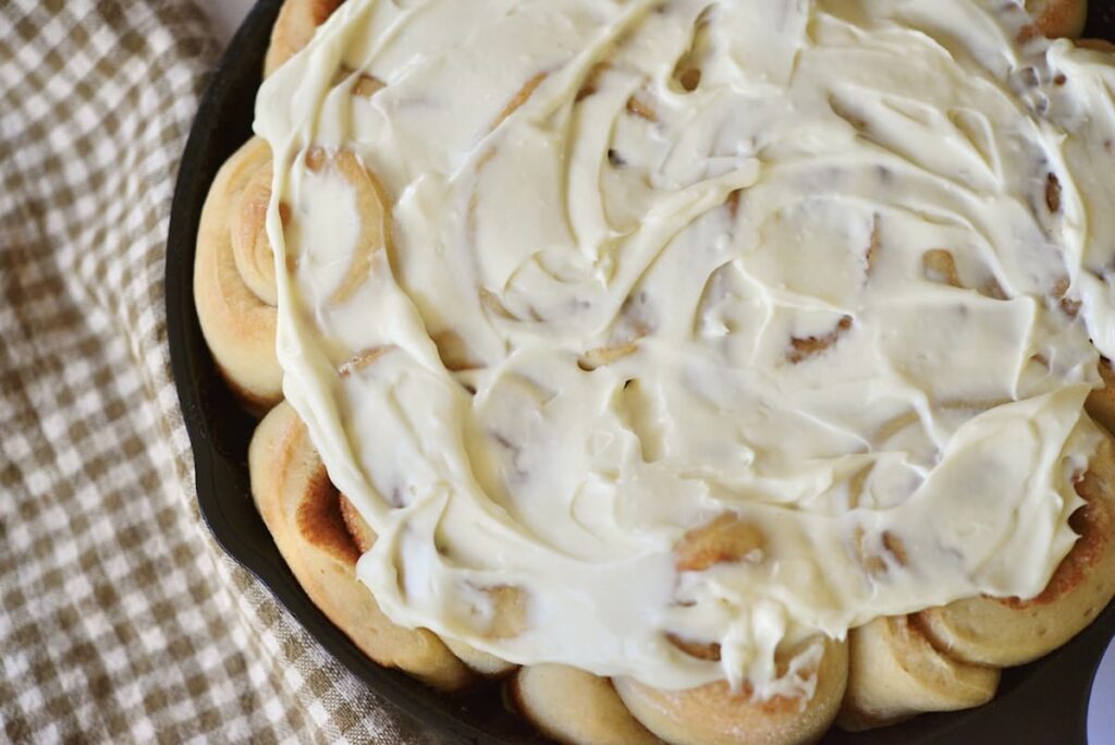 sourdough cinnamon rolls with glaze in cast iron skillet