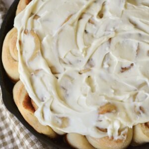 sourdough cinnamon rolls with glaze in cast iron skillet