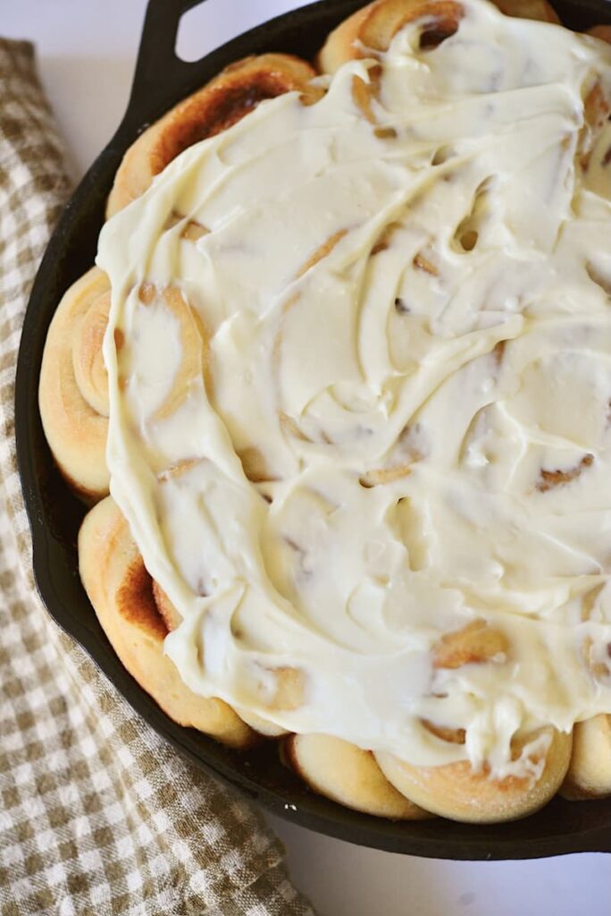 sourdough cinnamon rolls with glaze in cast iron skillet
