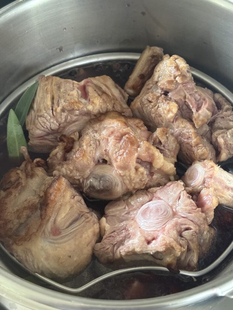 browned oxtail pieces in large pot