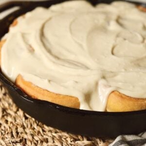 sourdough pumpkin cinnamon rolls with glaze in cast iron skillet