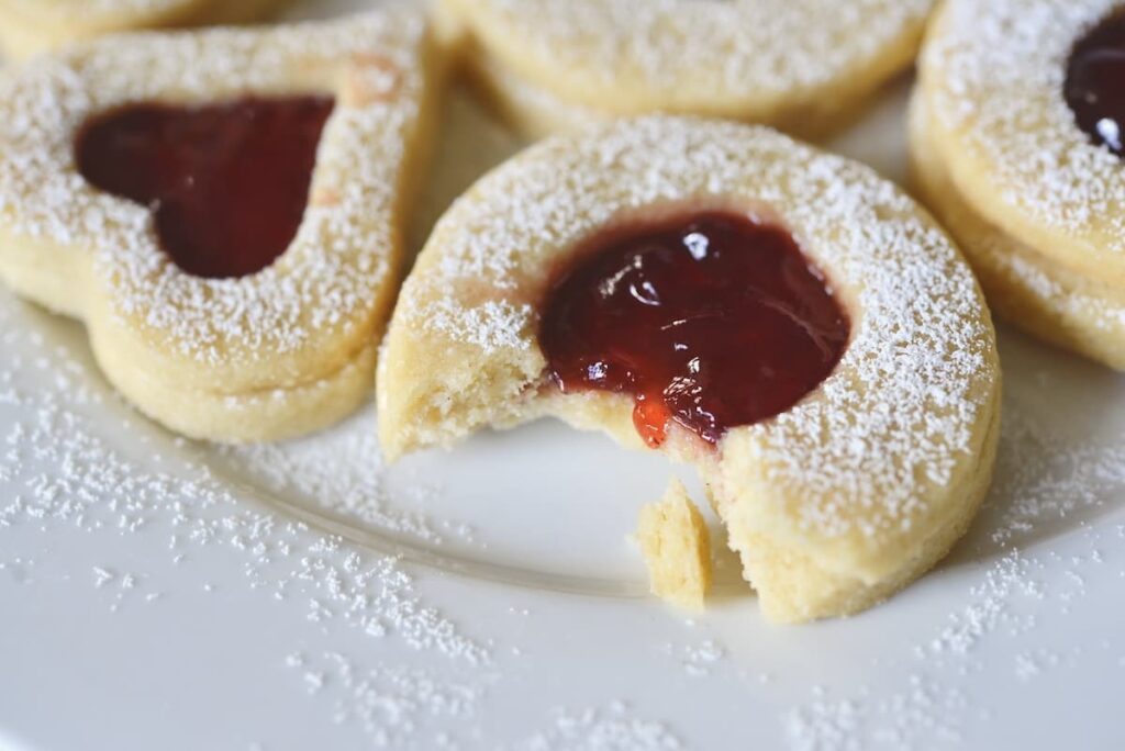 Linzer Kekse on cookie plate with one having a bite taken out