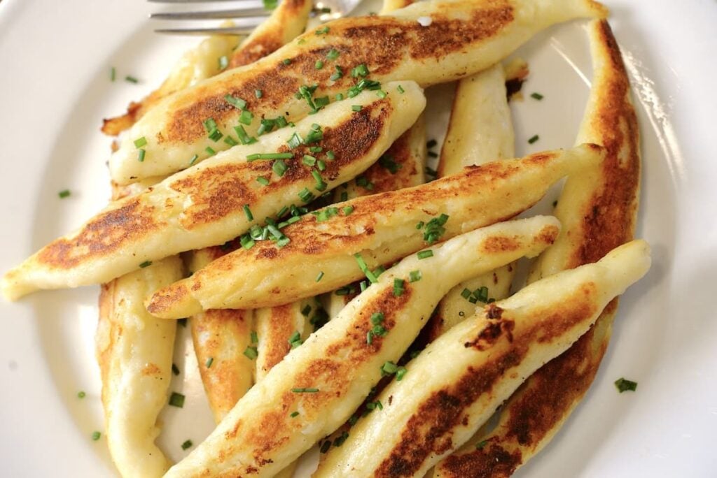 golden-brown German Schupfnudeln on plate sprinkled with chopped chives
