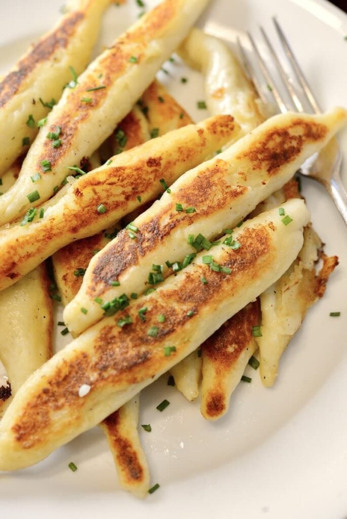 golden-brown German Schupfnudeln on plate sprinkled with chopped chives