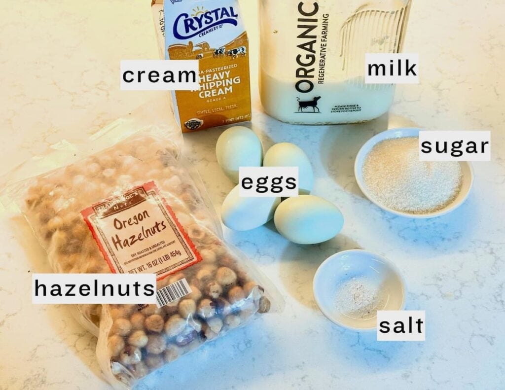 ingredients for homemade hazelnut ice cream: heavy whipping cream, milk, hazelnuts, four eggs, sugar and salt on a white countertop.