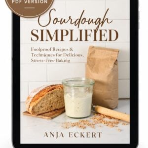 A tablet displaying the Sourdough Simplified PDF Ebook cover, which features a loaf of bread, a glass jar of starter, and a paper bag of grain.